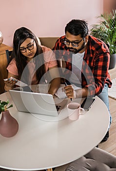 Serious wife and husband planning budget, checking finances, focused young woman using online calculator and counting