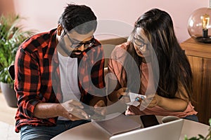 Serious wife and husband planning budget, checking finances, focused young woman using online calculator and counting