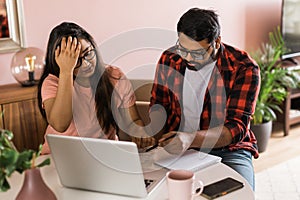 Serious wife and husband planning budget, checking finances, focused young woman using online calculator and counting