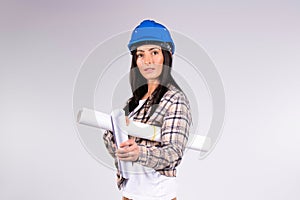 Serious woman architect in blue hard hat with blueprints on gray background with empty side space. The concept of gender