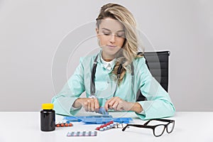 Serious woman doctor putting pills in a box