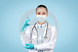 Serious woman doctor with syringe and safety gear