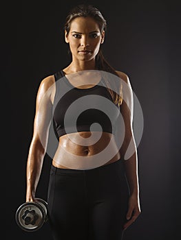 Serious woman with dumbbell over dark background