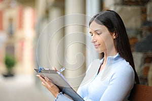 Serious woman filling out form in the street