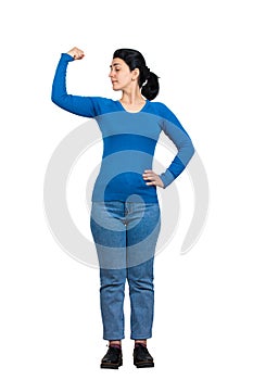 Serious woman full length portrait showing and flexing arm muscles, looking confident. Brave girl inner strength and power gesture