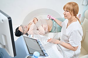 Serious woman gynecologist examining pregnant woman making ultrasound