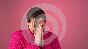 Serious woman with hands together reacts emotionally as if in prayer