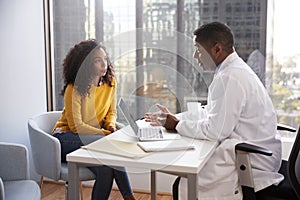 Serious Woman Having Consultation With Male Doctor In Hospital Office