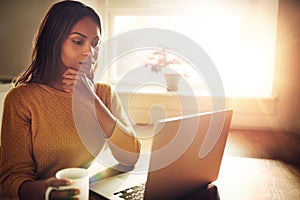 Serious woman holding chin and looking at computer