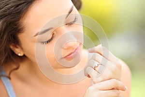 Serious woman looking at engagement ring in a park