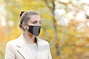 Serious woman with mask walking in a park in winter