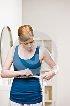 Serious woman measuring her waist