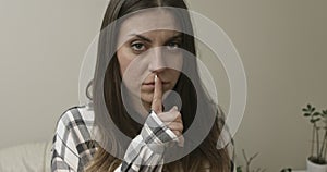 Serious woman placing her finger on mouth.