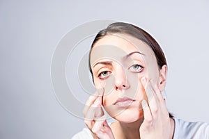 Serious Woman Pulling Down her Lower Eyelids photo