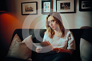 Serious Woman reading a Legal Contract at Home on the Sofa