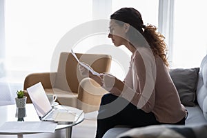 Serious woman reading letter looking concerned receive notification from bank