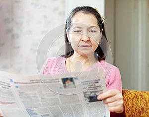 Serious woman reading newspaper