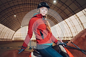 Serious woman riding a horse in the arena for equestrian sport