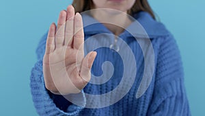 Serious woman showing rejecting gesture by stop finger sign. Enough signal. Lady on blue background.