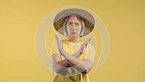 Serious woman showing rejecting gesture by stop sign. Don't play with me. Girl isolated on yellow background.