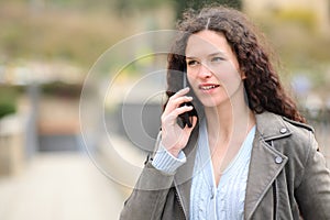 Serious woman talking on cell phone in the street