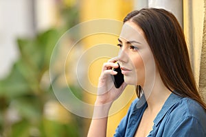 Serious woman is talking on phone in the street