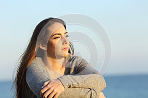 Serious woman thinking looking at horizon on the beach