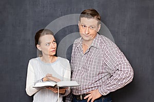 Serious woman is trying to pay attention of man to info in book