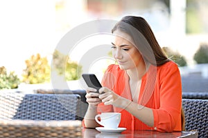 Serious woman is using a smart phone in a coffee shop