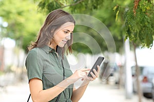 Serious woman walking using smart phone in the street