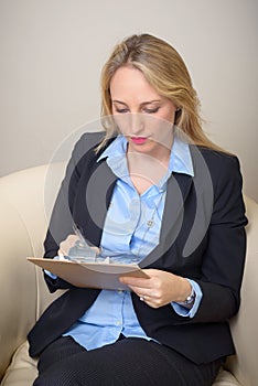 Serious woman writing on clipboard
