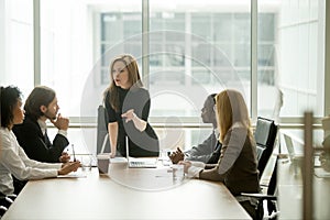 Serious woman boss talking to multiracial team at boardroom meet photo