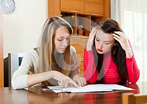 Serious women looking financial documents at table