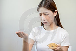 Serious, worried asian young woman, girl holding comb, show her hairbrush with long loss hair problem after brushing, hair fall