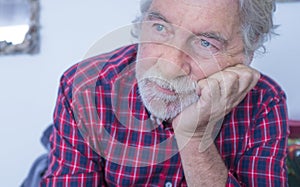 Serious and worried portrait of old senior caucasian man at home - people and depression or sadness for loneliness disease -