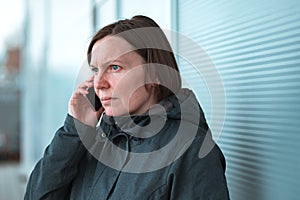 Serious worried woman talking on mobile phone on street