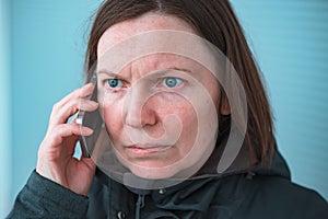 Serious worried woman talking on mobile phone on street