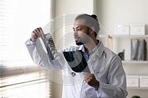 Serious young African American doctor examining radiography screening films