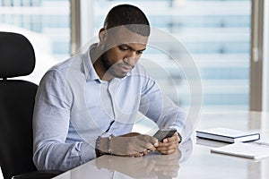 Serious young African business man reading, typing text message
