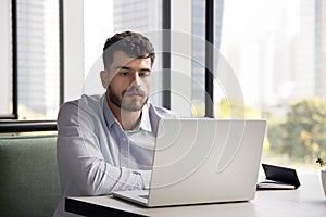 Serious young Arab entrepreneur man working in co-working cafe