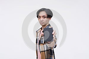 A serious young asian man holding an external HDD hard drive. Focus on face. Isolated on a white background
