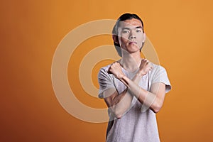 Serious young asian man showing stop gesture
