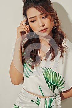Serious young Asian woman look away in tropical shirt on white background