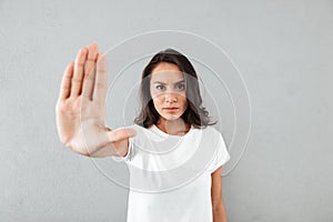 Serious young asian woman showing stop gesture with her palm