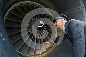 Serious young aviator inspecting the turbofan engine