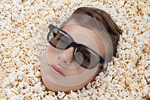 Serious young boy in stereo glasses looking out of popcorn