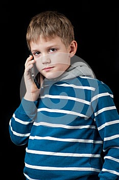 Serious young boy talking on mobile phone