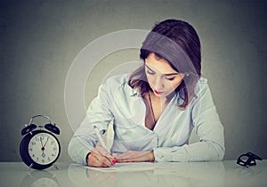 Serious young business woman writing a letter or filling out an application form