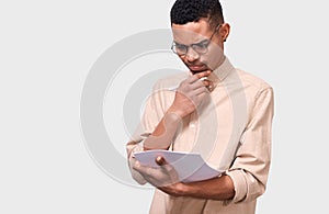 Serious young businessman in beige shirt analyzing financial reports posing on white studio background.