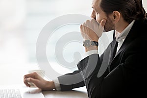 Serious young businessman in deep thought at workplace in office